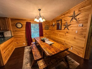 A wooden interior with a wooden table, benches, a chandelier, and star decorations on the walls.