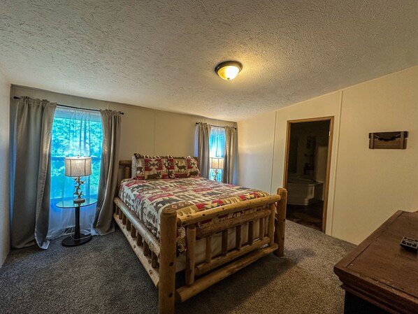 Un dormitorio con cama de madera, mesita de noche, lámpara y ventana con cortinas.