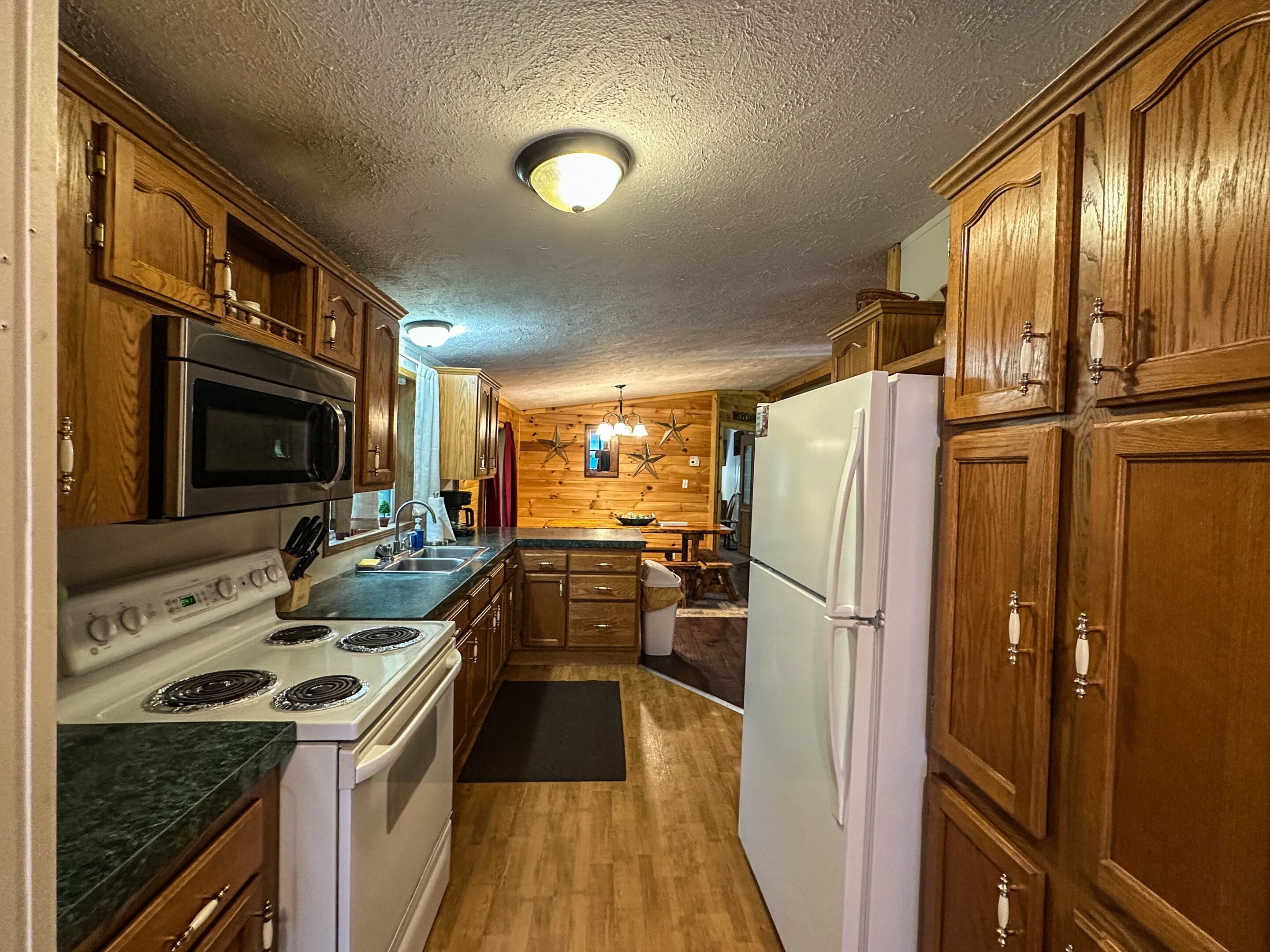 A kitchen with wooden cabinets, a microwave, stove, and refrigerator.