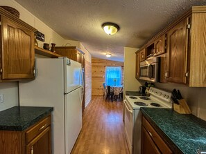 Cocina con gabinetes de madera, un refrigerador, una estufa y un microondas.