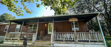 A rustic cabin with a porch, a sign reading 'Eagle's Landing,' and a wooden fence.