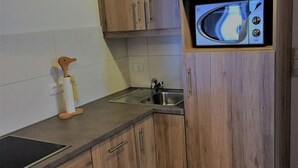 Una cucina con mobili in legno, un lavandino in acciaio inossidabile e un forno a microonde.