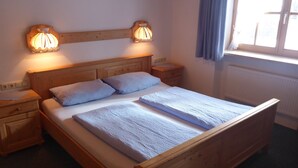 Un letto di legno con due cuscini e una coperta, affiancato da comodini con lampade.