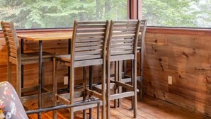 A wooden deck with a table and chairs, overlooking a forested area. - Secluded waterfront home, minutes from Lake Placid and Saranac Lake (Saranac Lake)