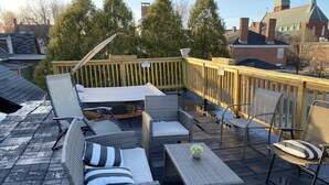 A rooftop patio with wicker furniture, a small table, and a wooden deck railing. - Fabulous studio apartment with roof deck (Portland)