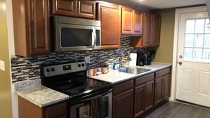 A kitchen with wooden cabinets, a stainless steel microwave, a stove, and a sink. - Fabulous studio apartment with roof deck (Portland)