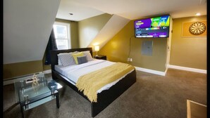 A bedroom with a bed, a glass coffee table, a TV mounted on the wall, and a dartboard. - Fabulous studio apartment with roof deck (Portland)