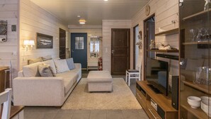 A cozy living room with a sofa, ottoman, and a TV stand. - Hil-lak-ka ii as 7 by Interhome (Äkäslompolo)