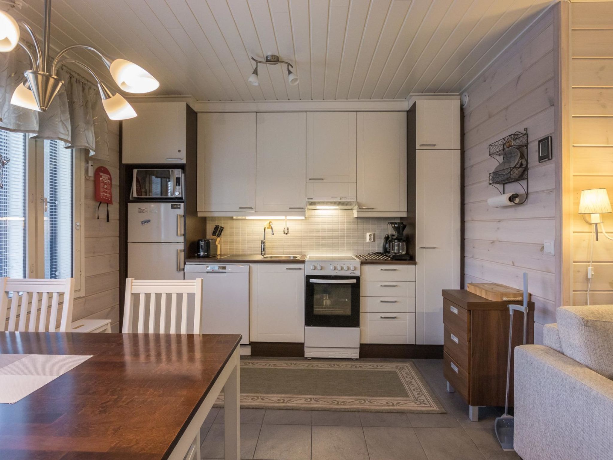 A compact kitchen with white cabinets, a built-in oven, a sink, and a coffee maker.