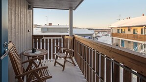 A balcony with wooden railings, a table, and two chairs. - Hil-lak-ka ii as 7 by Interhome (Äkäslompolo)