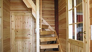 Un escalier en bois menant à une porte dotée d’un panneau de verre.