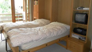 A bedroom with two beds, a wooden wardrobe, and a television. - Ammerten A17 by Interhome (Lenk)
