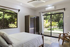 Ein Schlafzimmer mit Bett, Kleiderschrank und einer Glastür, die zu einem Garten führt.