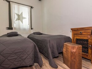A bedroom with two beds, a wooden cabinet, and a star-shaped window treatment.