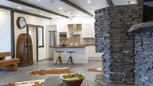 A rustic kitchen with stone walls, wooden beams, and a stone fireplace. - Kivipirtti by Interhome (Keuruu)
