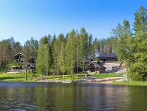 A lakeside property with multiple cabins, a dock, and a forested backdrop.