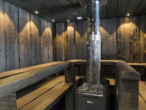 A sauna with wooden benches and a central heating unit. - Kivipirtti by Interhome (Keuruu)