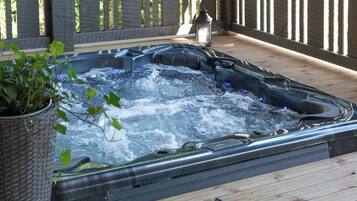 Ett bubbelbad på ett trädäck med en krukväxt i närheten.