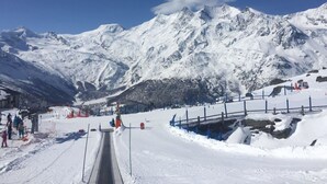 Une montagne enneigée, avec un télésiège, sous un ciel bleu dégagé.