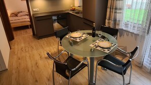 Une cuisine compacte avec des meubles en bois, une table à manger avec quatre chaises et un petit lit dans la pièce adjacente.