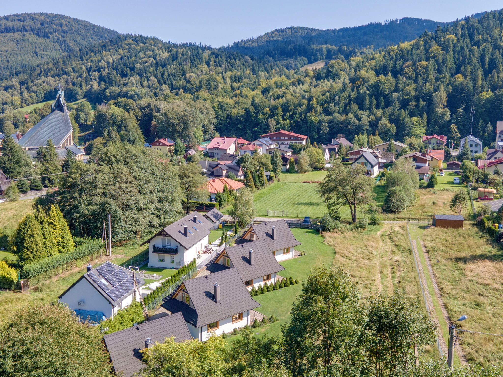 Un quartier résidentiel avec des maisons, une église et une chaîne de montagnes en arrière-plan.