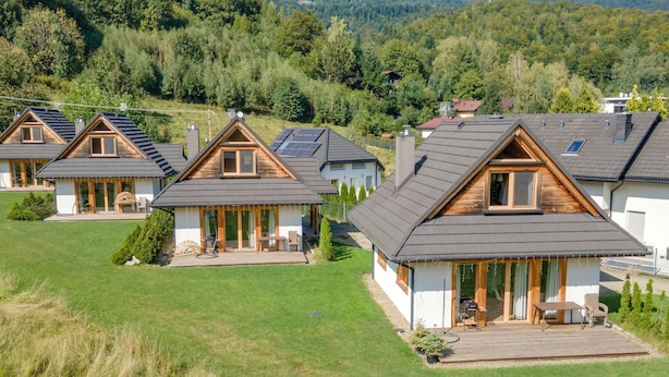 Una hilera de casas modernas con techos inclinados, terrazas de madera y ventanas amplias.