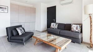 A modern living room with a grey sofa, a black armchair, and a glass-top coffee table. - Résidence Cita di Sali by Interhome (Porto Vecchio)