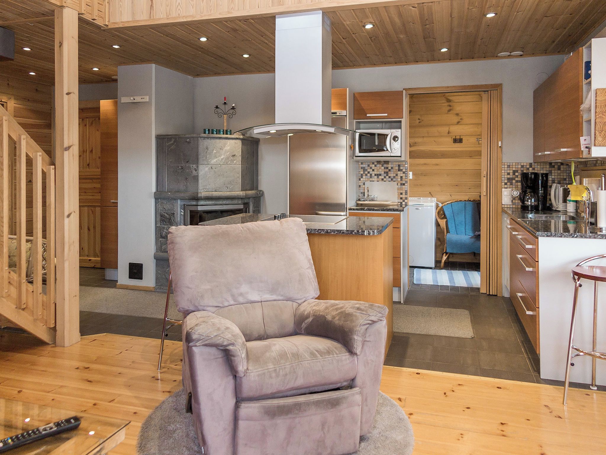 Una cocina moderna con una isla central, microondas integrado y una zona de estar con una silla acolchada.