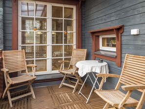 A wooden deck with four wooden chairs and a small round table, a window with blinds, and a wall-mounted light fixture. - Syvärinkulta b by Interhome (Nilsiä)