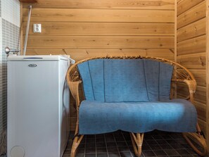A room with a white appliance, a wicker chair, and a wooden wall. - Syvärinkulta b by Interhome (Nilsiä)