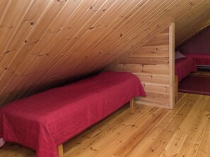 A single bed in a wooden room with sloped ceilings. - Syvärinkulta b by Interhome (Nilsiä)