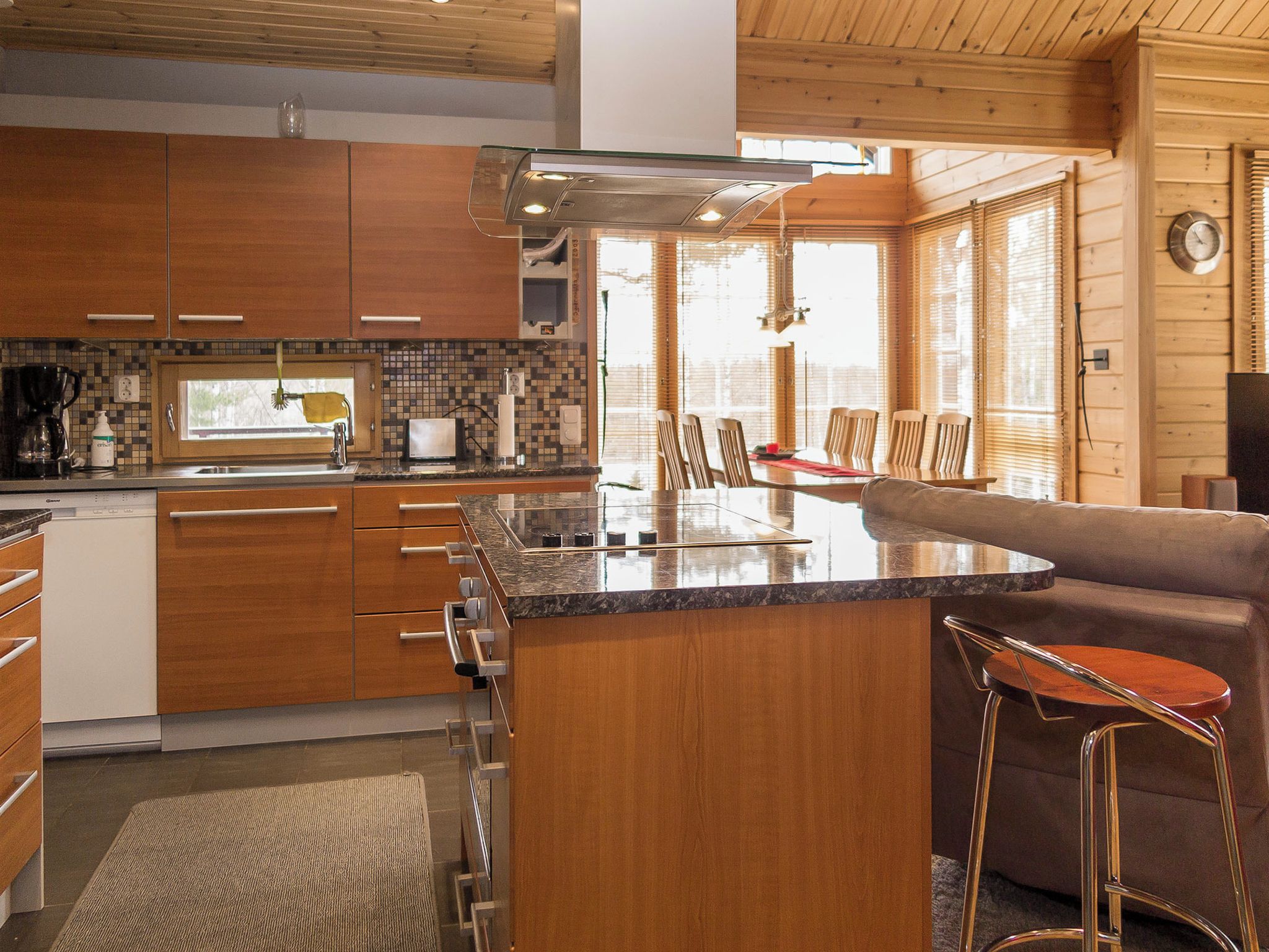 Une cuisine moderne avec des meubles en bois, une cuisinière encastrée et un grand îlot central doté de tabourets de bar.