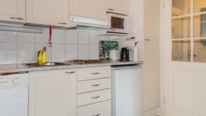 Een keuken met witte kastjes, een magnetron, een waterkoker en een koffiezetapparaat.
