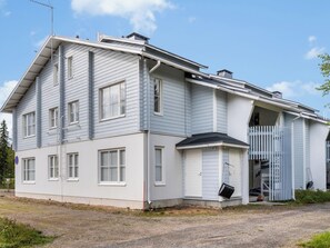 Un edificio de dos pisos con techo plano y un porche cubierto.