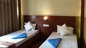 A hotel room with two single beds, each with a blue towel and white pillows. - Hotel Bajra (Tansen)