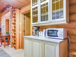 A wooden cabin interior with a kitchenette, including a microwave, coffee maker, and cabinets.