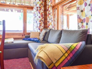 A cozy living area with a sofa, a colorful blanket, and a window with curtains.