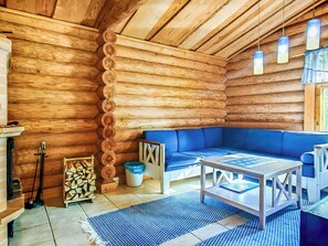 A log cabin interior with a blue sofa, a wooden table, and a hanging light fixture.