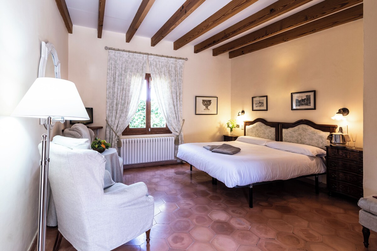 A bedroom with a bed, a chair, a lamp, and a window with curtains.