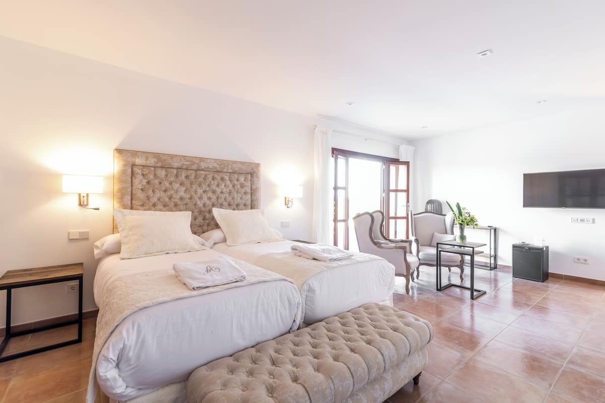 A hotel room with a large bed, a chair, a small table, and a TV mounted on the wall.