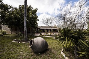 Une cour avec un grand pot en pierre, un palmier et un bâtiment doté d’un toit en tuiles.