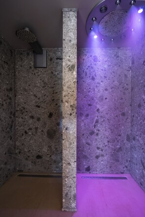 Ein Spa-Raum mit Steinwand, einer zentralen Säule und einer violett beleuchteten Decke.
