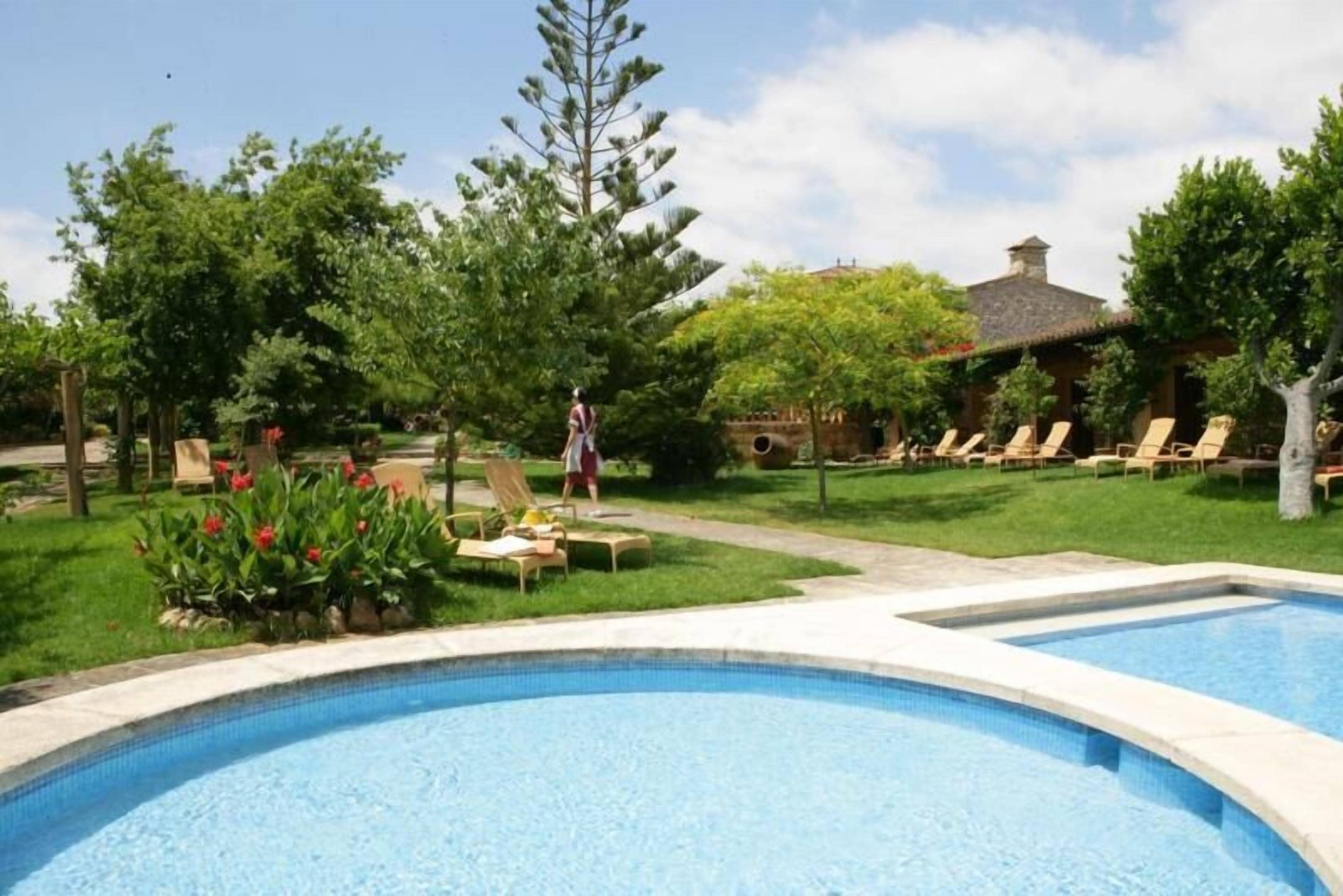 Ein Schwimmbecken mit Liegestühlen und einer Person, die gerade geht.