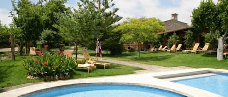 A swimming pool with lounge chairs and a person walking.