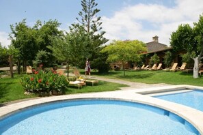 Une piscine avec des chaises longues et une personne qui se promène.