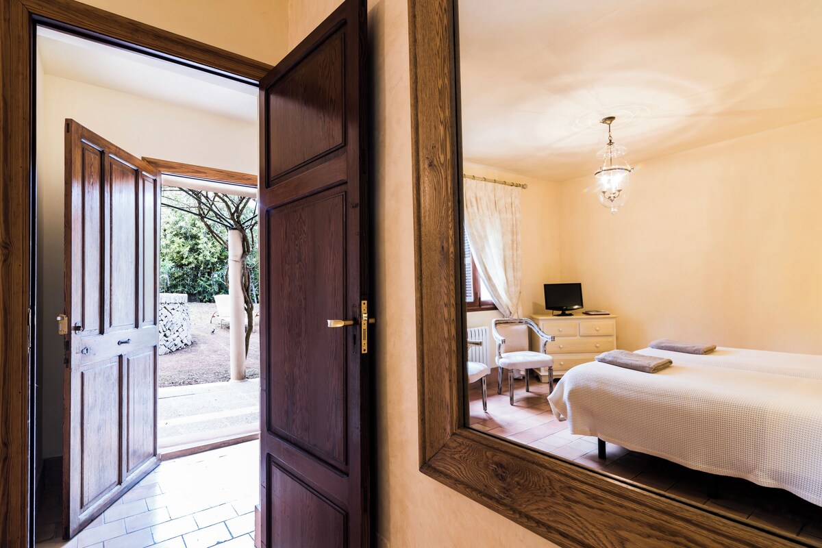 A bedroom with a large mirror, a bed, a desk, and a chair.