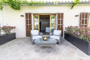 An outdoor patio with two white cushioned chairs, a glass-top table, and a small flower arrangement. - Aumallia Hotel & Spa (Felanitx)