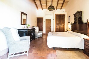 A bedroom with a large bed, a dresser, a chair, and a desk with a mirror. - Aumallia Hotel & Spa (Felanitx)