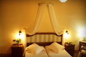 Une chambre à coucher avec un lit à baldaquin, des lampes de chevet et une table de chevet ornée d’un vase de fleurs.
