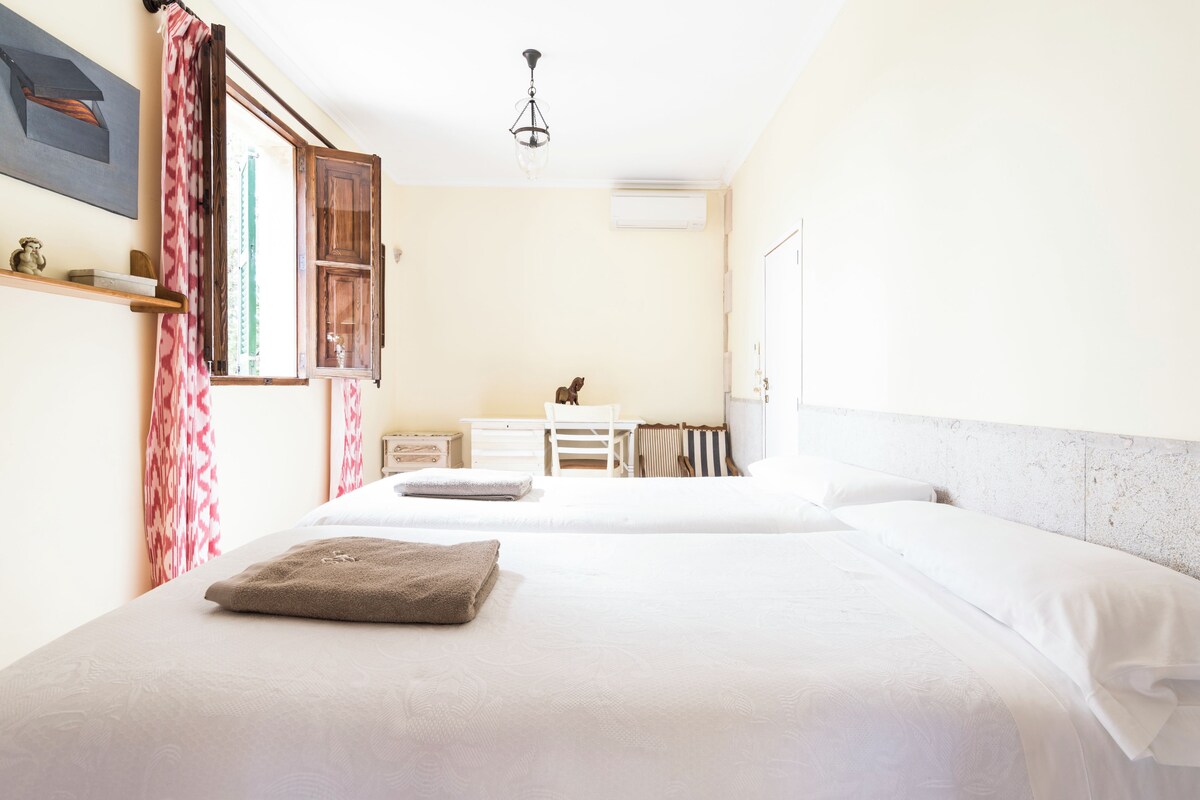 A bedroom with two beds, a desk, and a radiator.